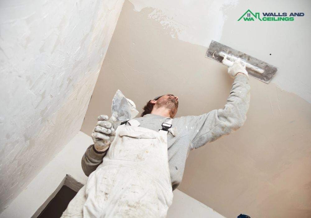 Tradesman plastering timber beams inside ceiling of house in [Location]